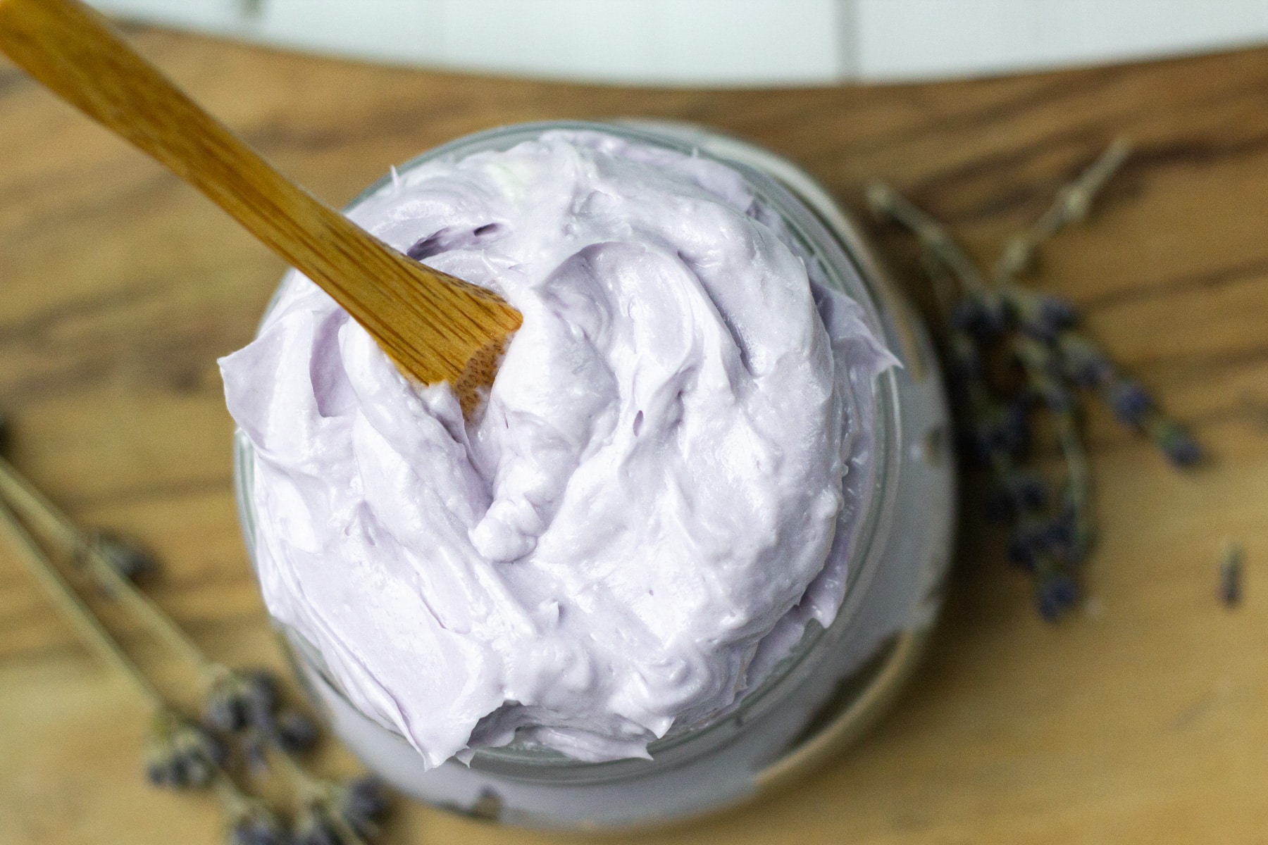 body butter in glass jar with wooden spoon.