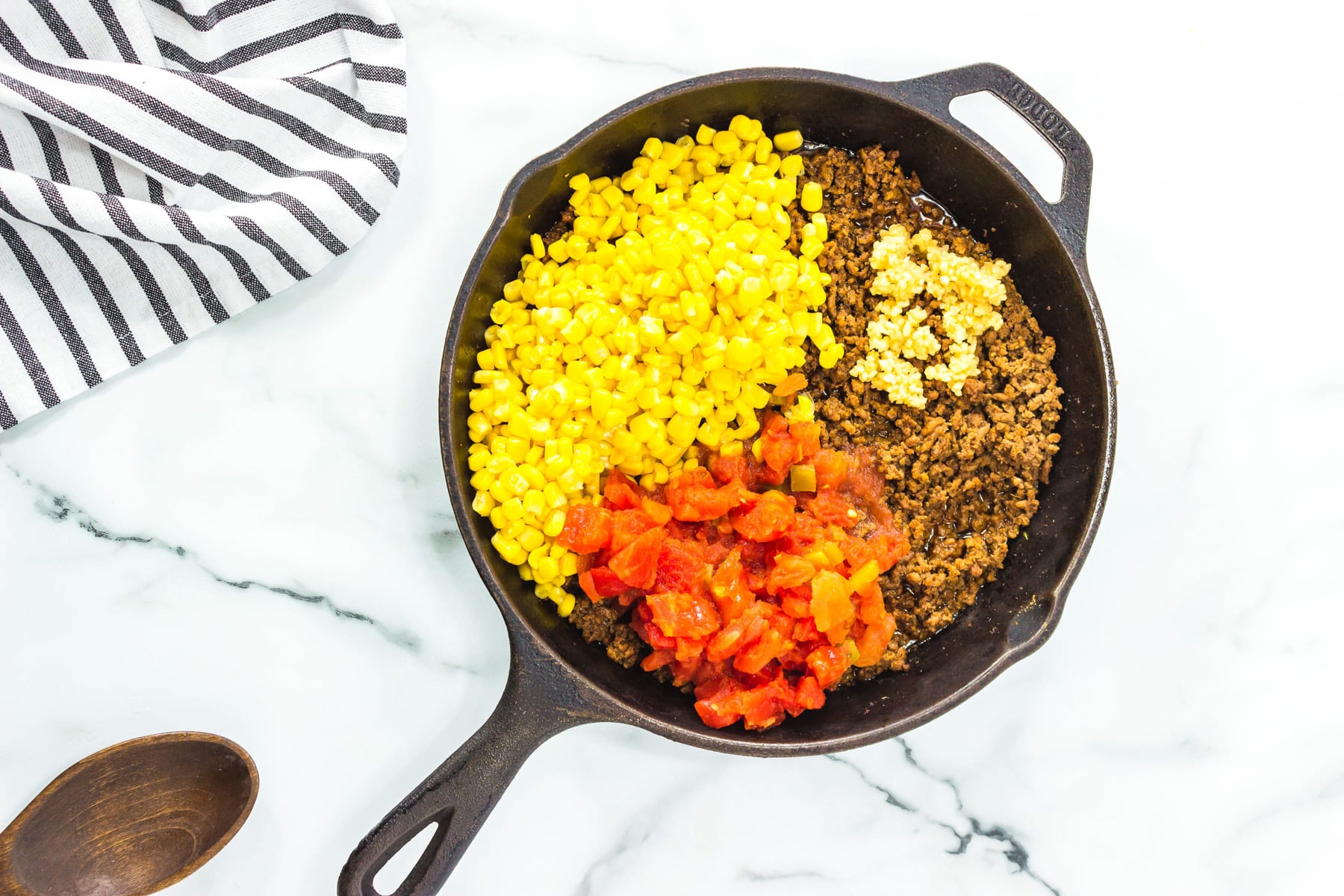 skillet with meat, corn, tomatoes and garlic.