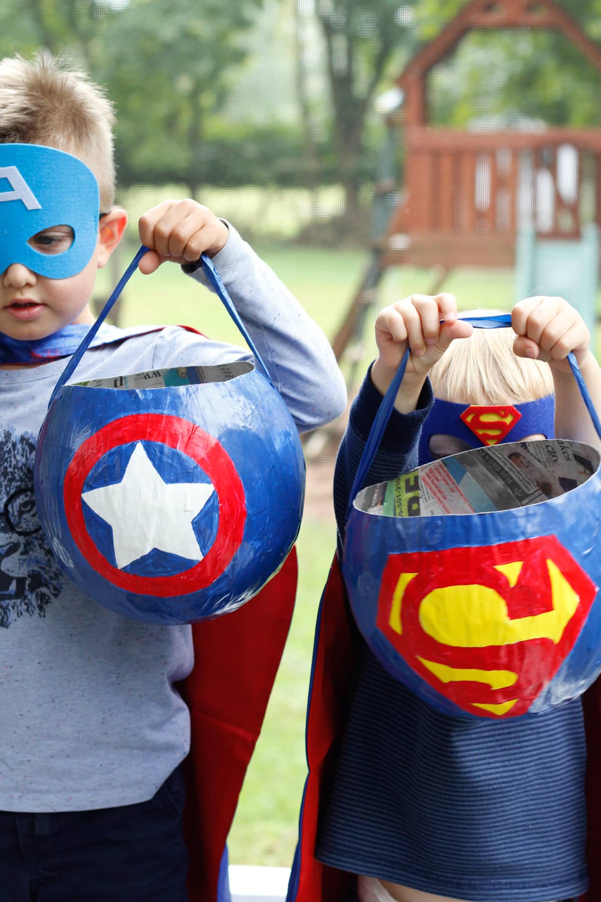 boys holding superhero themed treat baskets.