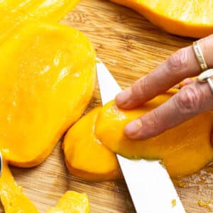 hand slicing mango half lenghtwise.